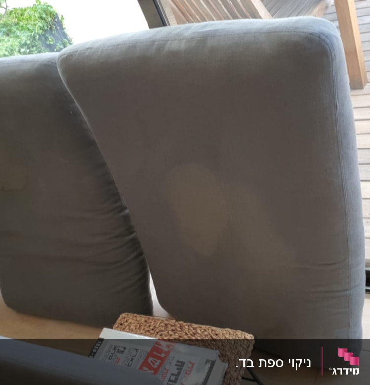 כריות ספה אפורות עם כתמים, מונחות על הרצפה